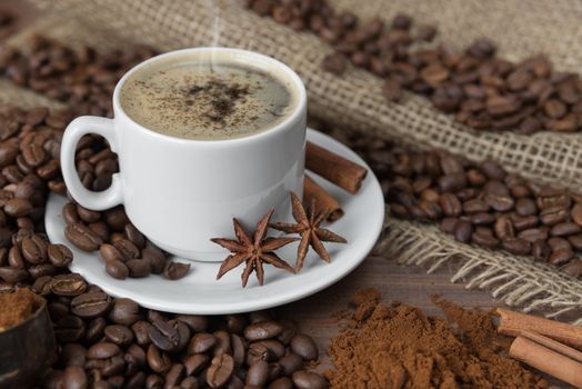 Cup of coffee with spices on the background of coffee beans