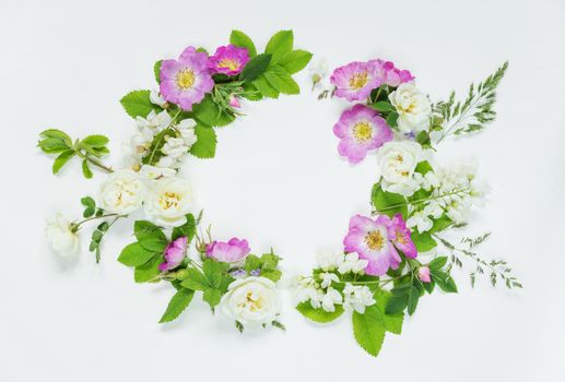 Decorative composition in retro style consisting of pink wild rose and white locust flowers with green leaves on white background. Top view, flat lay