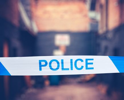 British Police Tape Around A Crime Scene In A Grungy Urban Alley