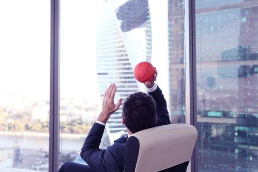 Business man playing with a basketball at the office