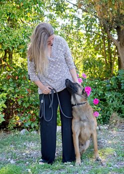 woman and belgian shepherd malinois in a garden