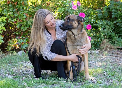 woman and belgian shepherd malinois in a garden