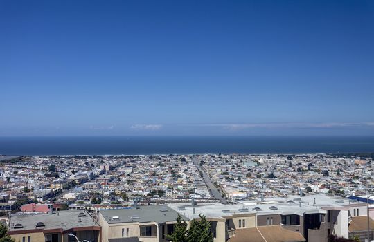 A mountain view of San Francisco's Sunset District. To the left you can see Golden Gate Park and windmill. At the oceans edge is the Great Highway. 