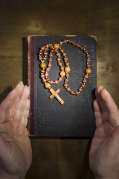 Female hands with rosary and an old book