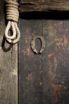 Rusty horseshoe and rope on an old wooden door