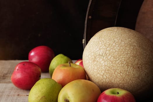 Melon and apples in basket on wooden floor.