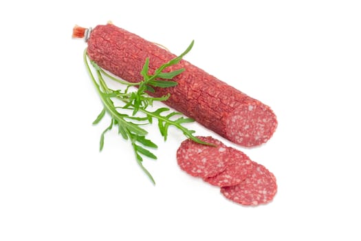 Partly sliced salami and fresh twig of the arugula on a light background
