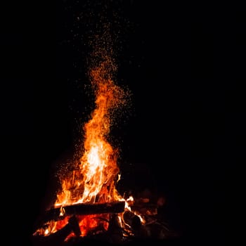 Campfire with flying sparks isolated on black background