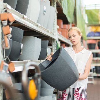 Beautiful young caucasian woman choosing the right item for her apartment in a modern home decor furnishings store. Shopping in retail store.