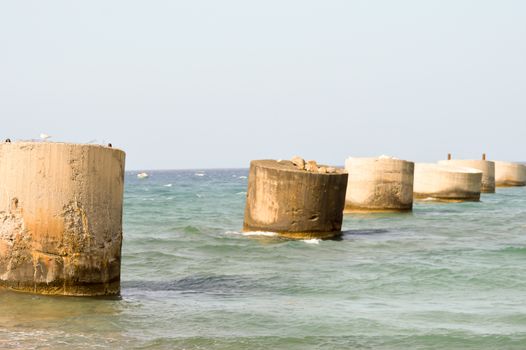 Several old concrete feet used as supports for a pipeline on the ocean of Crete