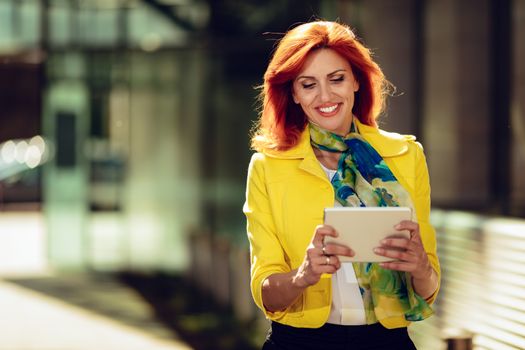 Smiling successful businesswoman using digital tablet in office district.