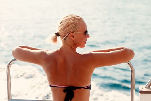 Rear view of a beautiful young woman enjoying on the deck. They are on cruise and looking for away.