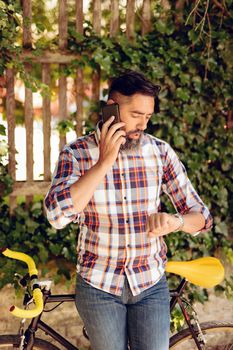 Casual businessman with bike talking on smartphone.