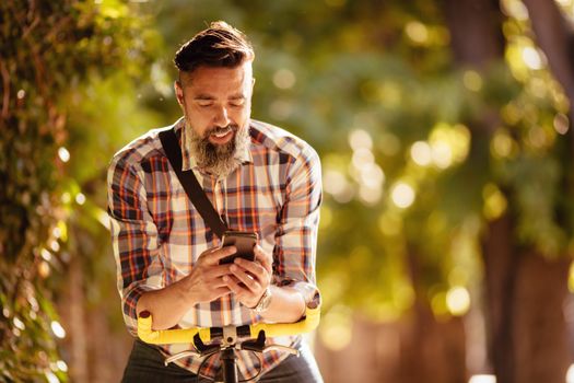 Handsome man with bike sending text message.