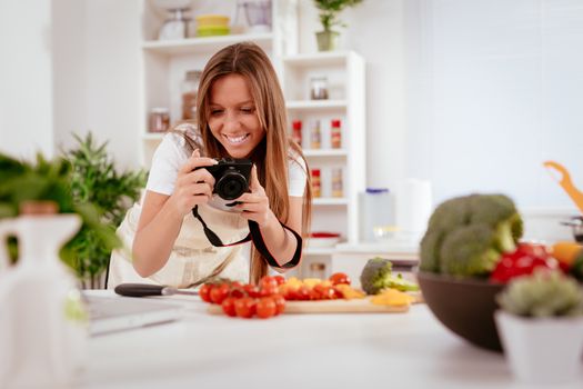 Beautiful young woman taking photo of healthy salad with digital photo camera for her blog.