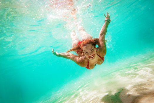 Beautiful young woman diving underwater in the sea. 