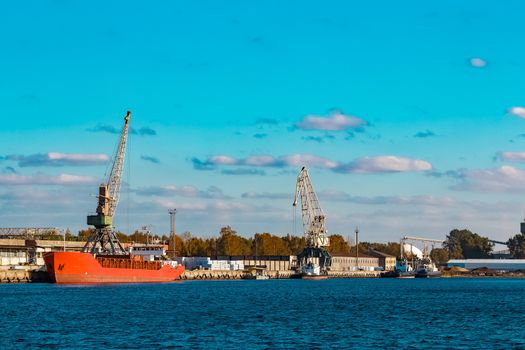 Red cargo ship moored and loading in the port