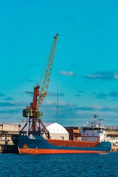 Blue cargo ship moored and loading at the port