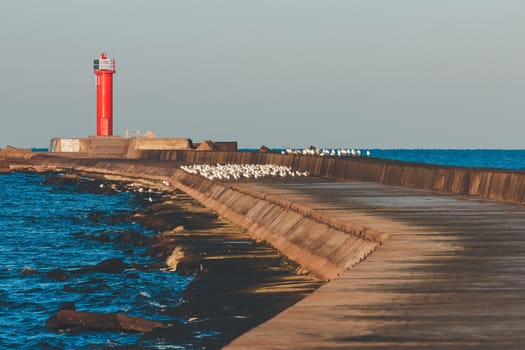 Red lighthouse on breakwater jetty at Baltic sea