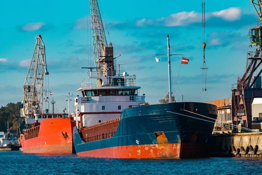 Blue cargo ship moored and loading at the port