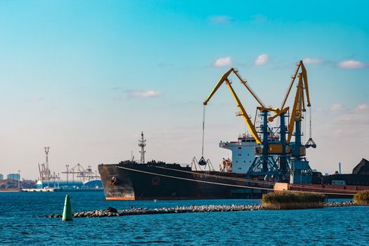 Black cargo ship loading with a coal at the port