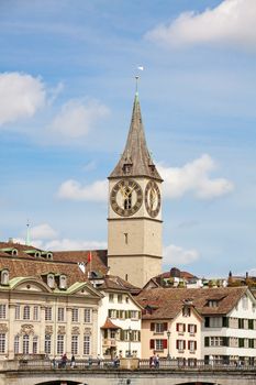 Zurich, Switzerland - June 10, 2017: Church Saint Peter in downtown Zurich, bridge over river Limmat in front.