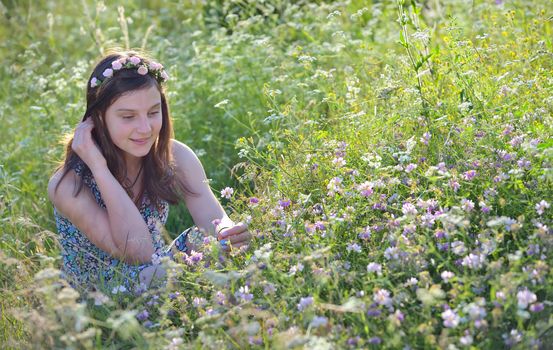 Girl  in summer field with flowers in hair