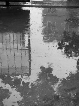 PHOTO OF RAINDROPS AND REFLECTION ON PLAIN CONCRETE GROUND