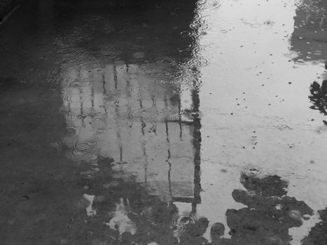 PHOTO OF RAINDROPS AND REFLECTION ON PLAIN CONCRETE GROUND