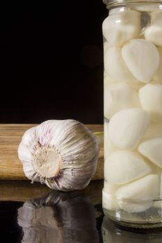 Marinated and fresh garlic with a grater on a dark background