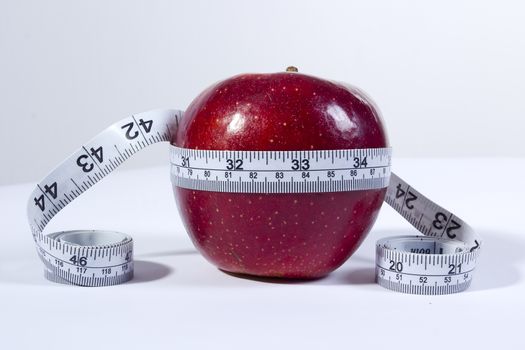 concept image of a tape measure around a red apple