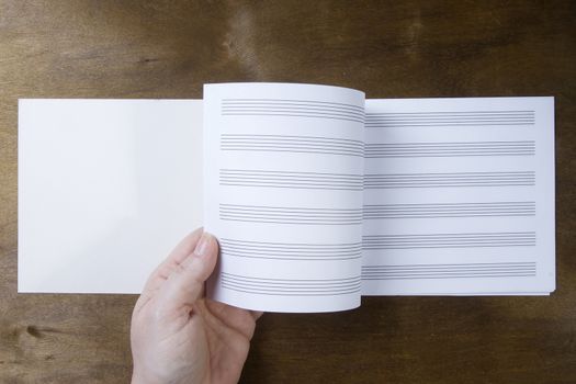 Hand turns over the pages of a notebook on a wooden background