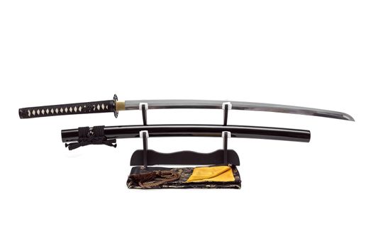 Japanese sword and scabbard on stand  white background, black silk bag at front.