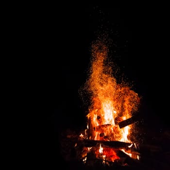 Campfire with flying sparks isolated on black background