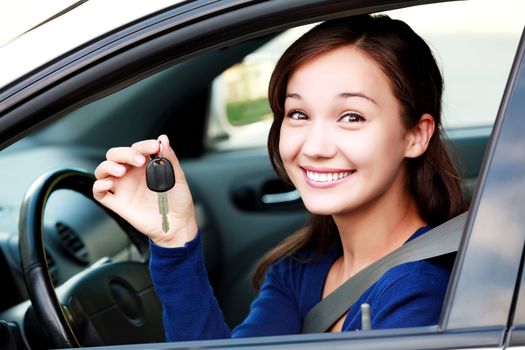 Beautiful young smiling happy girl shows the car key in her hand