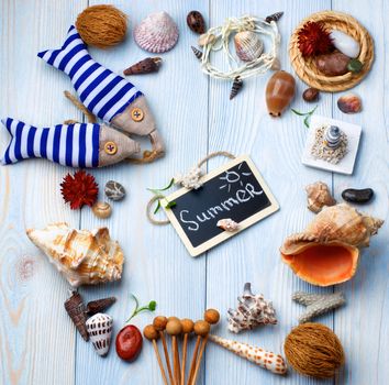 Summer Vacations Concept with Handmade Decorations, Various Shells, Dry Plants  and Chalk Board with Inscription Summer closeup on Light Blue Wooden background