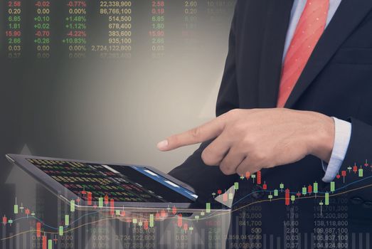 business man Trading concept using the tablet with financial graph on cityscape background, Double exposure style.