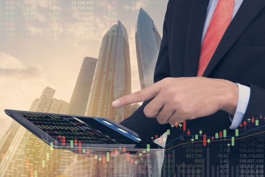 business man Trading concept using the tablet with financial graph on cityscape background, Double exposure style.