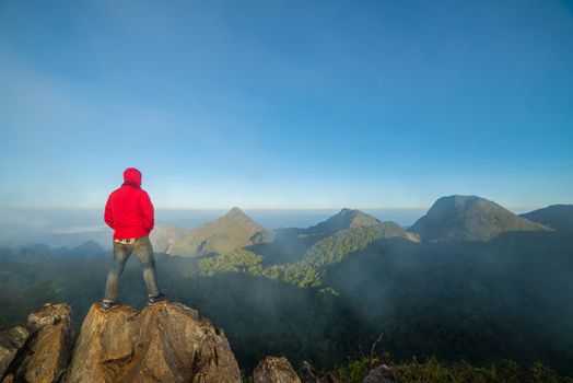 Man on top of mountain sitting on the rock watching a view landscape at Doi Luang Chiang Dao, ChiangMai Thailand.