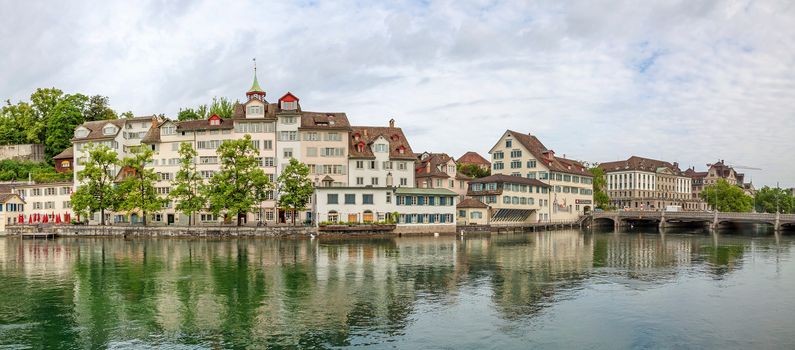 Zurich, Switzerland - June 10, 2017: Panorama of river Limmat, sight Taufergedenkplatte (left) and historic buildings riversides. View from Limmatquai.