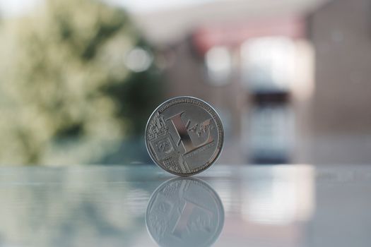 Digital currency physical silver Litecoin coin on the table near the window.