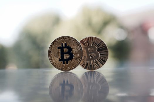 Digital currency two physical gold bitcoin coins on the table near the window.