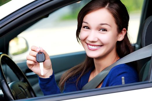 Beautiful young smiling happy girl shows the car key in her hand