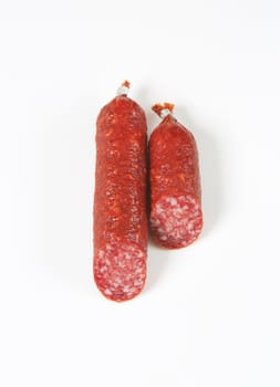two pieces of salami sausage on white background