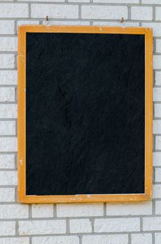 Empty large slate boards with wooden frame on a stone wall.