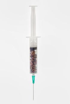 Coffee beans in syringe on white background