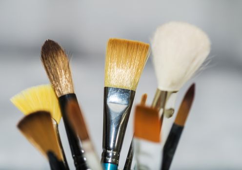 Various artists paint brushes of different sizes and shapes