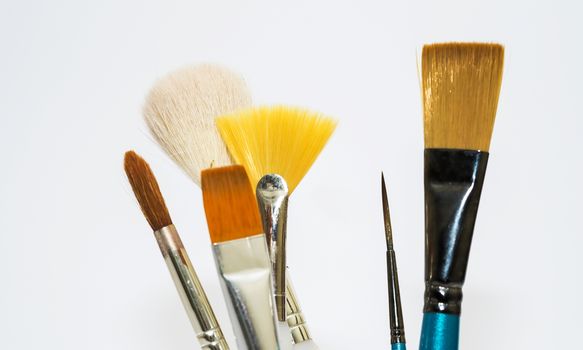 Various artists paint brushes of different sizes and shapes