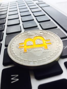 Cryptocurrency physical silver bitcoin coin on black computer keyboard.