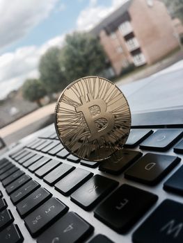 Cryptocurrency physical gold bitcoin coin on the keyboard near window.